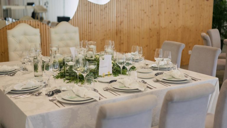 Mesa de casamento posta, com copos, louça e um arranjo de flores ao centro