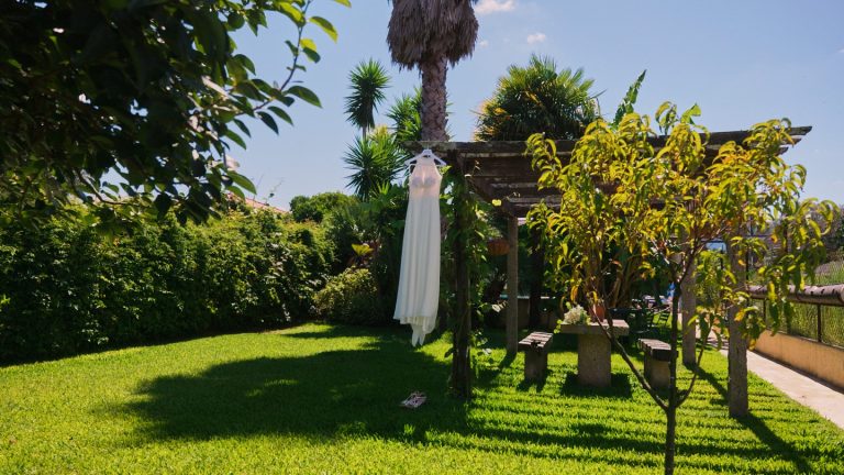 Vestido de noiva pendurado num caramanchão, no jardim de uma quinta
